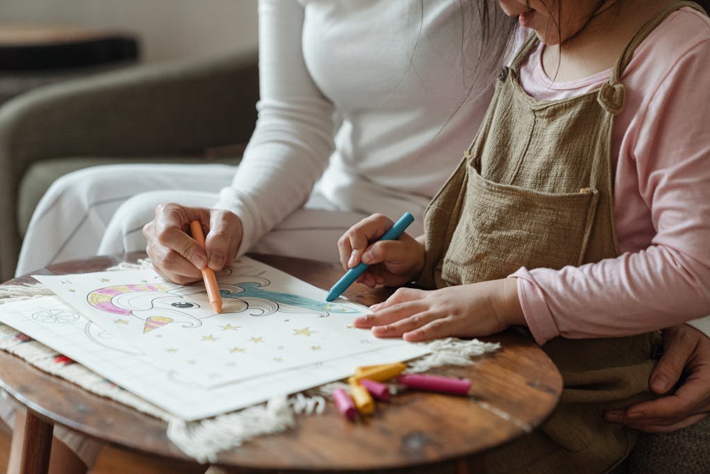 A mother and daughter share a joyful moment coloring with crayons at home, fostering creativity and bonding.