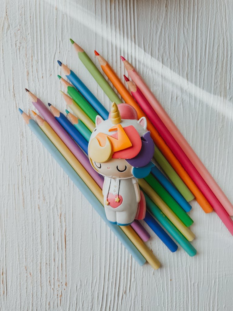 Charming unicorn figurine surrounded by vibrant colored pencils on a textured white background.